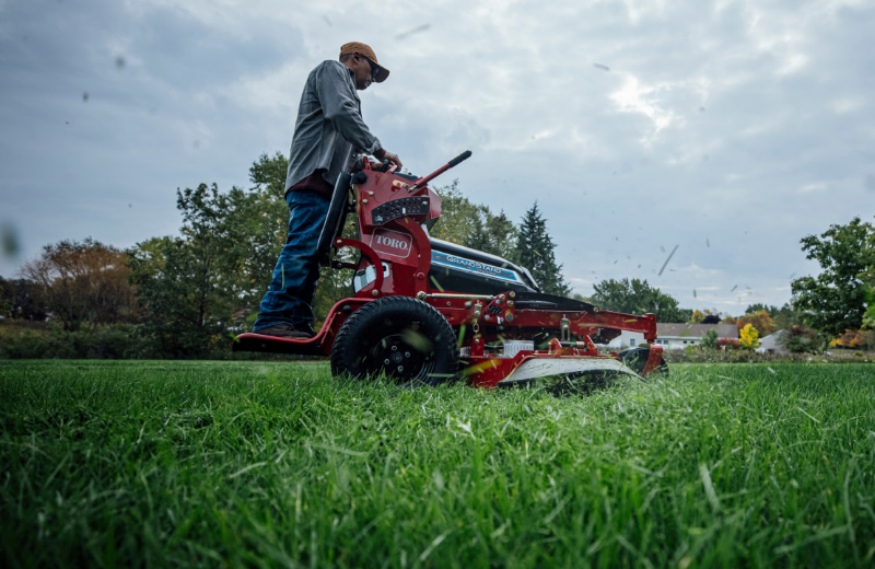 A man uses a Toro Grandstand Revolution from Kenney Machinery to mow a lawn.