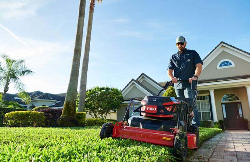 A man uses a Toro HD 21 Revolution from Kenney Machinery to mow a lawn.