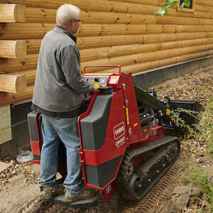 a man uses a toro dingo to clear a patch of turf